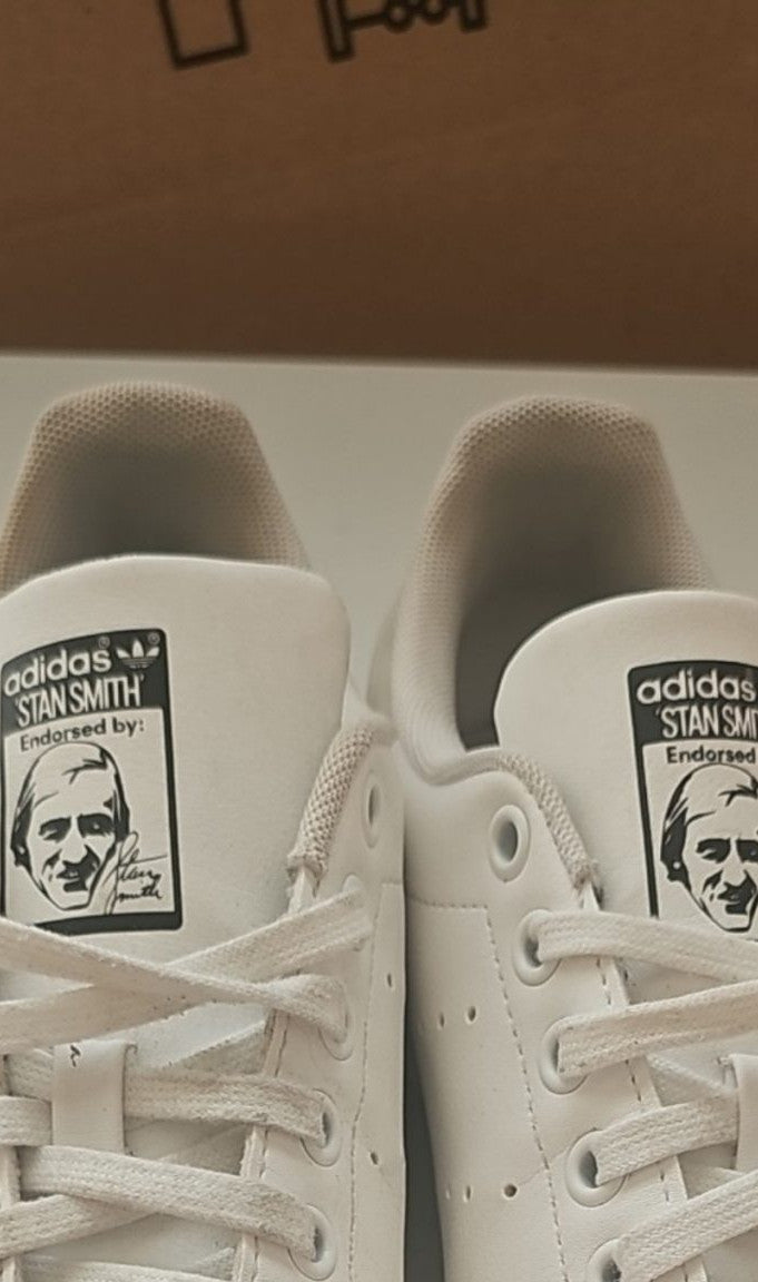 Adidas white Stan Smith sneakers with perforated three stripes and logo on tongue.