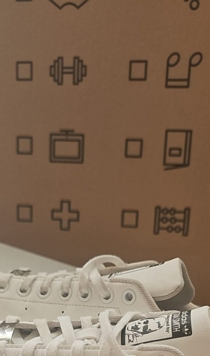 Adidas white Stan Smith sneakers with perforated three stripes and logo on tongue.