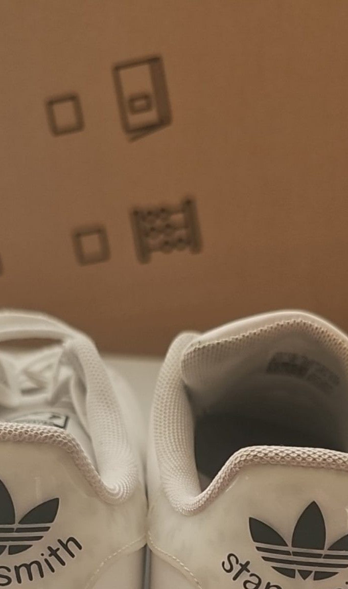 Adidas white Stan Smith sneakers with perforated three stripes and logo on tongue.