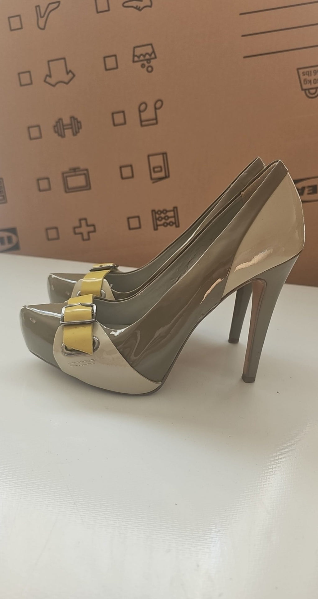 ALDO beige and taupe patent leather high heel shoes with yellow buckle detail.