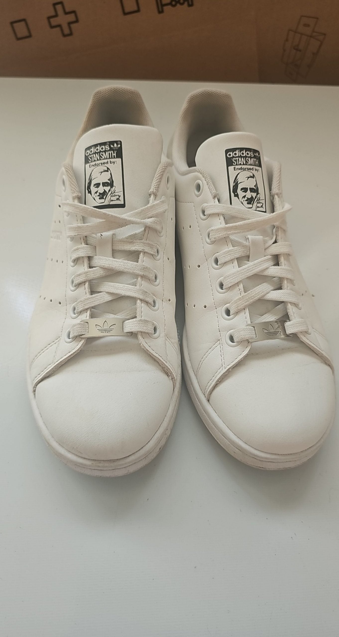 Adidas white Stan Smith sneakers with perforated three stripes and logo on tongue.