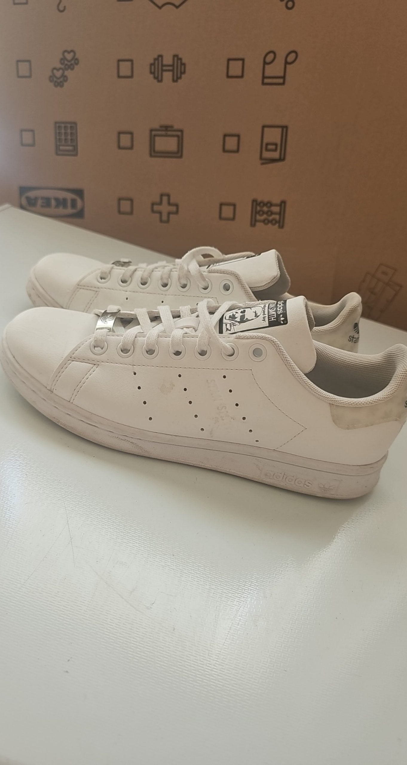 Adidas white Stan Smith sneakers with perforated three stripes and logo on tongue.