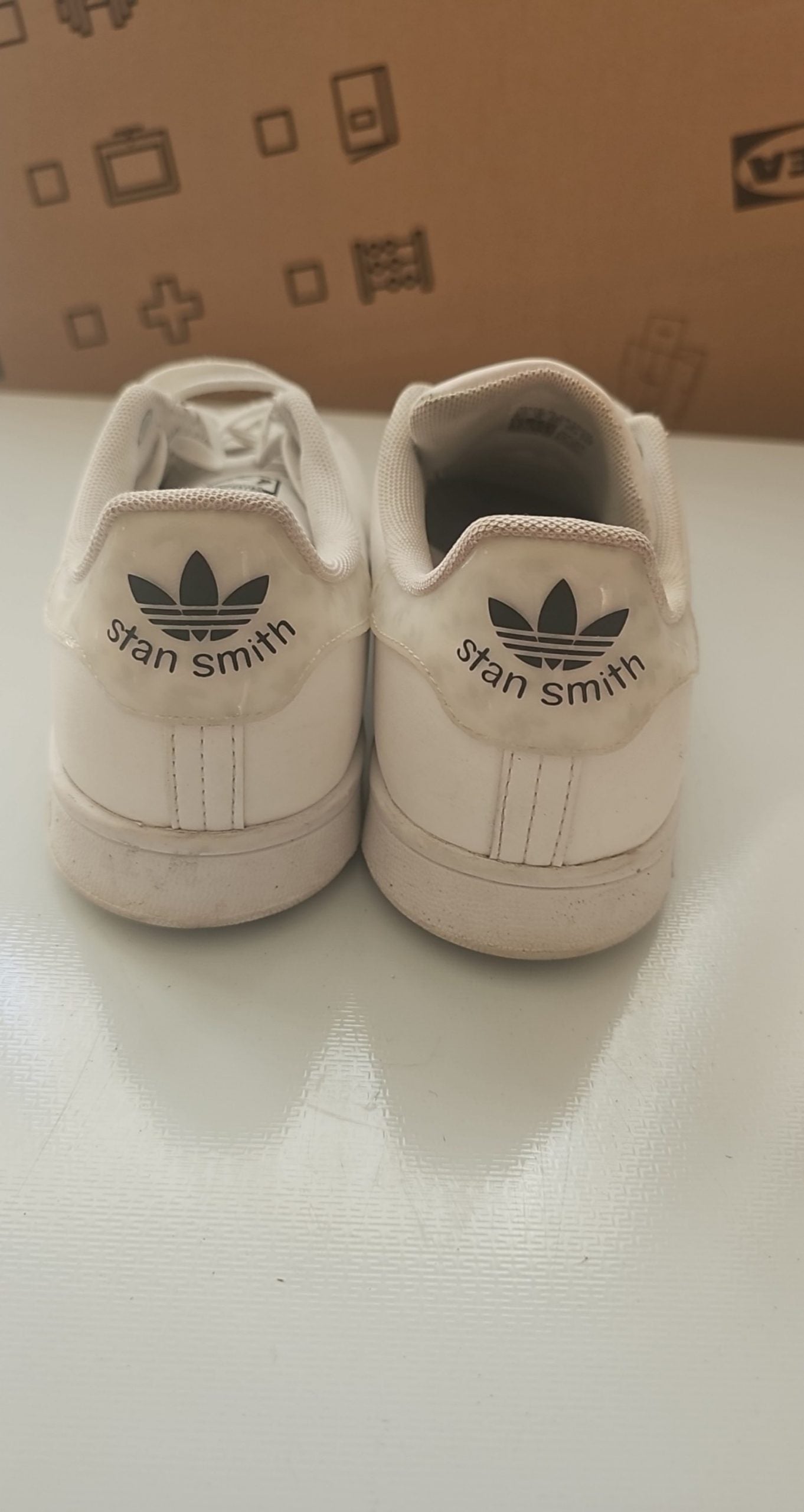Adidas white Stan Smith sneakers with perforated three stripes and logo on tongue.